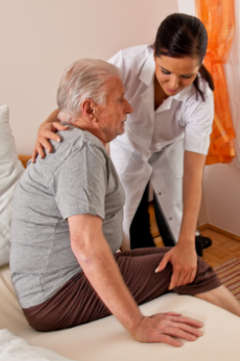 nurse helping a senior man out of bed 