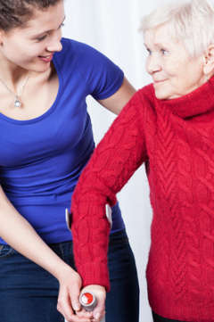 young woman helping an elderly woman walk 