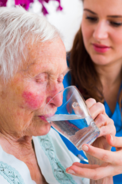nurse helping woman drink water