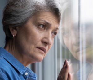 depressed older woman looking out window