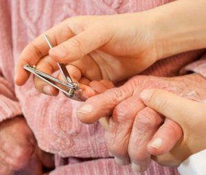 caregiver cutting woman's nails